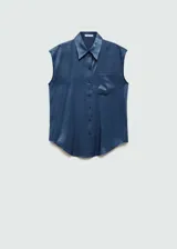 Camisa azul sin mangas de tejido fluido y satinado, con cuello camisero, cierre frontal con botones y bolsillo de parche en el pecho.