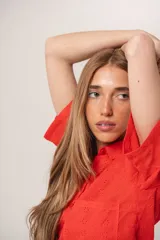 Camisa corta color rojo con broderie, cuello clásico, cierre frontal con botones, manga corta y bolsillo en el pecho.