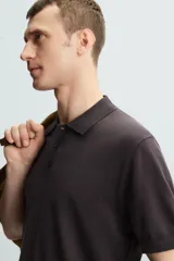 Polo negro de punto tejido en hilatura con algodón y lyocell, corte regular fit, cuello solapa con cierre frontal de botonadura, manga corta y acabados en rib.