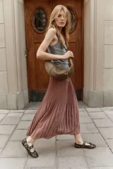 Pollera larga plisada color marrón, de tiro alto con elástico fino en la cintura y bajo sobrehilado con vuelo.