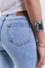 Pantalón de jean celeste de tiro medio, corte ajustado hasta la rodilla y acampanado en la parte inferior, con lycra y terminación desflecada.