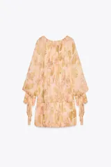 Vestido corto con estampado floral en tonos pastel, cuello redondo con volantes y escote pico ajustable con lazadas. Manga larga acabada en puño con lazadas y bajo con pliegues.