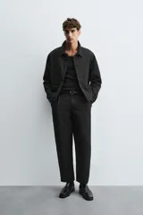 Pantalón negro relaxed fit confeccionado en tejido con algodón, lino y lyocell. Cintura con detalle de pliegues frontales dobles, bolsillos delanteros y traseros. Cierre frontal con cremallera y botón.