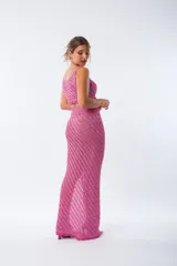 Conjunto tejido de color fucsia brillante, compuesto por un top corto con tirantes finos y una falda larga con abertura lateral.