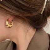 Aros dorados de estilo moderno y diseño elegante, fabricados en material hipoalergénico.