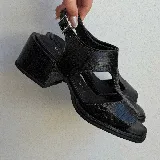 Sandalias de cuero vacuno color marrón con textura tipo cocodrilo, taco ancho y plataforma. Diseño con puntera descubierta y tira ancha sobre el empeine con aberturas laterales. Cierre con hebilla en el tobillo.