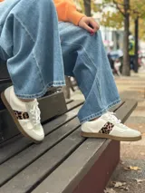 Championes blancos de cuero sintético con cordones y estampado animal print de leopardo en los laterales.