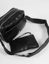 Cartera de hombro color bordó, confeccionada en cuero vegano, con un compartimento principal con cierre, un bolsillo frontal con cierre y un bolsillo trasero con cierre. Tiene una correa ajustable.