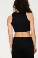 Musculosa corta de punto acanalado de algodón, color negro, con cuello redondo y sisas con ribete fino.