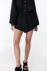 Short pollera blanco de tela arrugada con volados y detalles de encaje.
