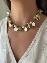 Collar corto con cuentas de piedra natural en tonos blanco, marrón y verde, con dijes circulares dorados y blancos.