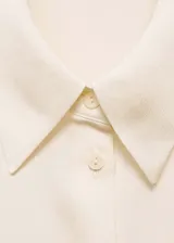 Camisa color crema de manga larga con puños abotonados y cuello camisero.