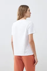 Remera blanca de algodón con cuello redondo y mangas cortas. Estampa frontal con bordado de flores y frase 'Just keep flowing'.