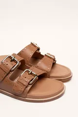 Sandalias marrones de cuero vacuno con doble tira y hebillas metálicas ajustables.