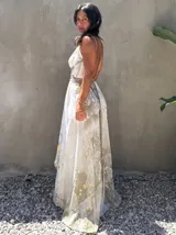 Vestido largo de tela fluida, color verde esmeralda con estampado abstracto en tonos turquesa y detalles dorados. Diseño asimétrico con un solo tirante tejido en el hombro.