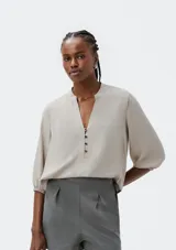 Blusa color verde claro, de mangas 3/4 con elástico en los puños, escote en V con botones y corte holgado.