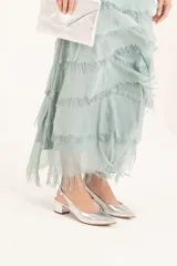 Zapato plateado de cuero sintético con punta fina, talón descubierto y taco cuadrado bajo.