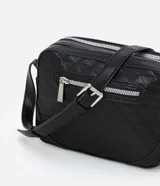 Bolso bandolera pequeño color marrón con textura geométrica en relieve. Tiene correa larga regulable, cierre de cremallera y separadores internos.