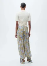 Pantalón largo de gasa con estampado floral en tonos verde, celeste y marrón. Diseño balloon con detalle de lazos en el bajo y tiro medio.
