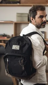 Mochila negra de tela Oxford con base de nobuk color beige, dos bolsillos frontales con cierre y tiradores de cuero. Correas de hombro acolchadas.