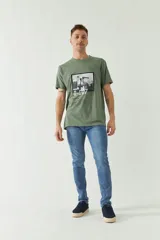 Remera verde militar de manga corta con estampa fotográfica en blanco y negro de un edificio y texto con la dirección de la marca.