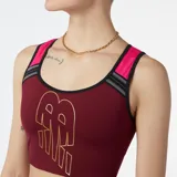 Top deportivo New Balance Achiever Crop, color borgoña con logo dorado estampado en el frente. Tiene espalda deportiva con tirantes fucsia y detalles en gris.