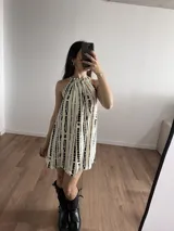 Minivestido blanco con estampado de líneas verticales negras, cuello halter con ajuste elástico y corte suelto.