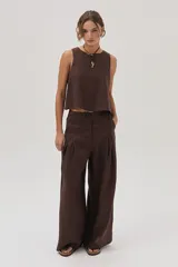 Pantalón marrón de lino, de pierna ancha, con elástico en la cintura, pinzas en el frente y bolsillos laterales y traseros.