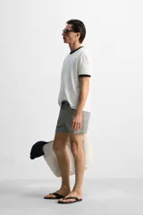Short de baño con textura seersucker a rayas verticales azul marino y blanco. Tiene cintura elástica ajustable con cordón, bolsillos frontales y traseros, aberturas laterales en el bajo y forro interior.