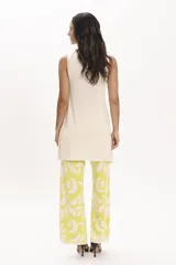 Pantalón palazzo de tejido de punto color amarillo con estampado de hojas blancas.