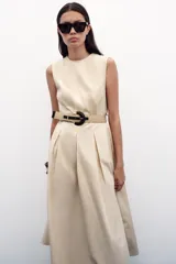 Vestido midi color beige, de popelín, con cuello redondo y sin mangas. Presenta cintura entallada con pinzas, cinturón y falda evasé.