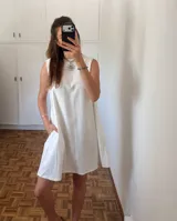 Vestido corto sin mangas confeccionado en lino de algodón, con silueta amplia y recta. Presenta bolsillos laterales y un tajo en la espalda con lazo regulable.