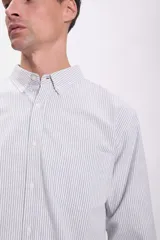 Camisa de hombre de corte clásico, confeccionada en tela Oxford con rayas verticales grises y blancas. Tiene cuello abotonado, manga larga con puños abotonados y un bolsillo en el pecho.