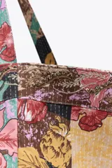 Maxi bolso de mano tipo tote bag con estampado floral multicolor sobre fondo amarillo.