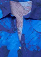 Camisa azul con estampado floral, de corte recto, cuello camisero y manga larga.