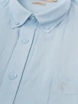 Camisa de manga larga azul, de lino y poliéster, con cuello abotonado y bolsillo en el pecho.