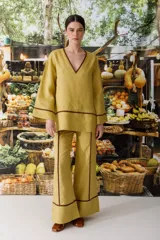 Blusa color crudo de lino con cuello en V y ribete marrón.