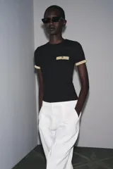 Camiseta blanca de corte slim fit, cuello redondo y manga corta. Detalle de acabados en tricot con hilo metalizado color dorado en mangas y bolsillo.