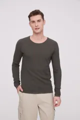Sweater de algodón color verde oscuro, de manga larga y cuello redondo a la base. Presenta un tejido texturizado de punto fino.