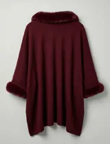 Ruana o poncho negro de tejido suave, con cuello y puños adornados con apliques de piel sintética (faux fur).