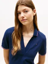 Vestido azul marino de corte slim, tipo chomba, con cuello polo y tapeta con botones. Detalles de ribete rojo y blanco en cuello y mangas. Logo de Tommy Hilfiger bordado en el pecho. Confeccionado en algodón regenerativo y elastano.