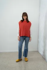 Chaleco de punto grueso color coral, con cuello alto y sisas amplias.