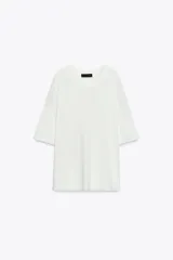 Remera blanca de punto liso, corte amplio, cuello redondo y manga corta.