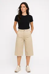 Bermuda de jean color beige, corte amplio y largo hasta la rodilla.