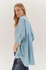 Sobrecamisa celeste de corte recto, con cuello mao, mangas 3/4 con puños y cierre frontal con botones. Tiene dos bolsillos de parche en el pecho.
