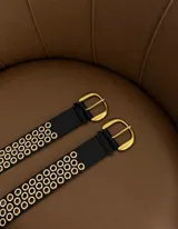 Cinturón negro de cuero ecológico con hebilla dorada y múltiples ojales dorados.