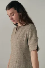 Vestido a la rodilla color beige, con escote en V, mangas cortas con detalle de tajo, bolsillos laterales y forro interior.