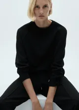 Sweater negro de tejido fluido con cuello redondo y mangas largas.