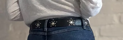Cinturón negro de cuero con hebilla plateada y apliques de estrellas plateadas.