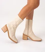 Bota corta color crema con textura de reptil, caña media, punta cuadrada, cierre lateral y taco de madera.